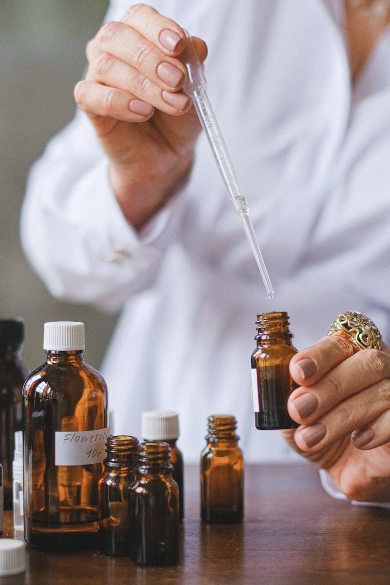Close-up of hands handling amber glass bottles during an aromatherapy session.