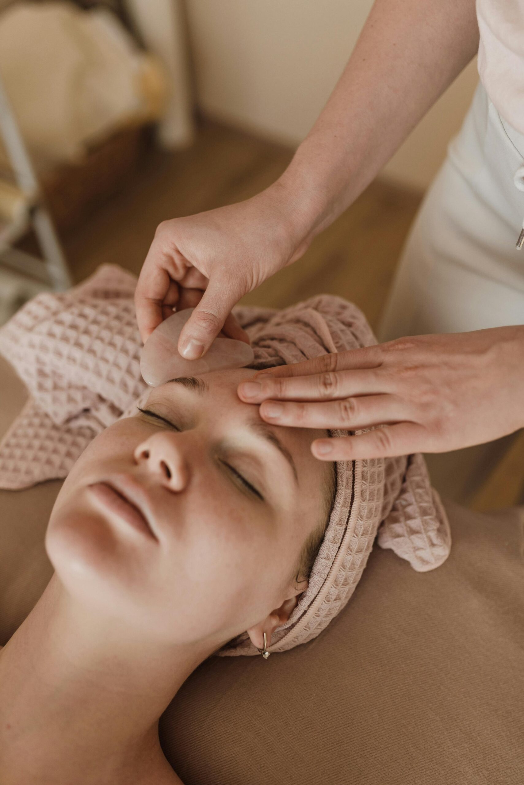 Woman enjoying a soothing facial massage with gua sha tool, promoting relaxation and skin care.